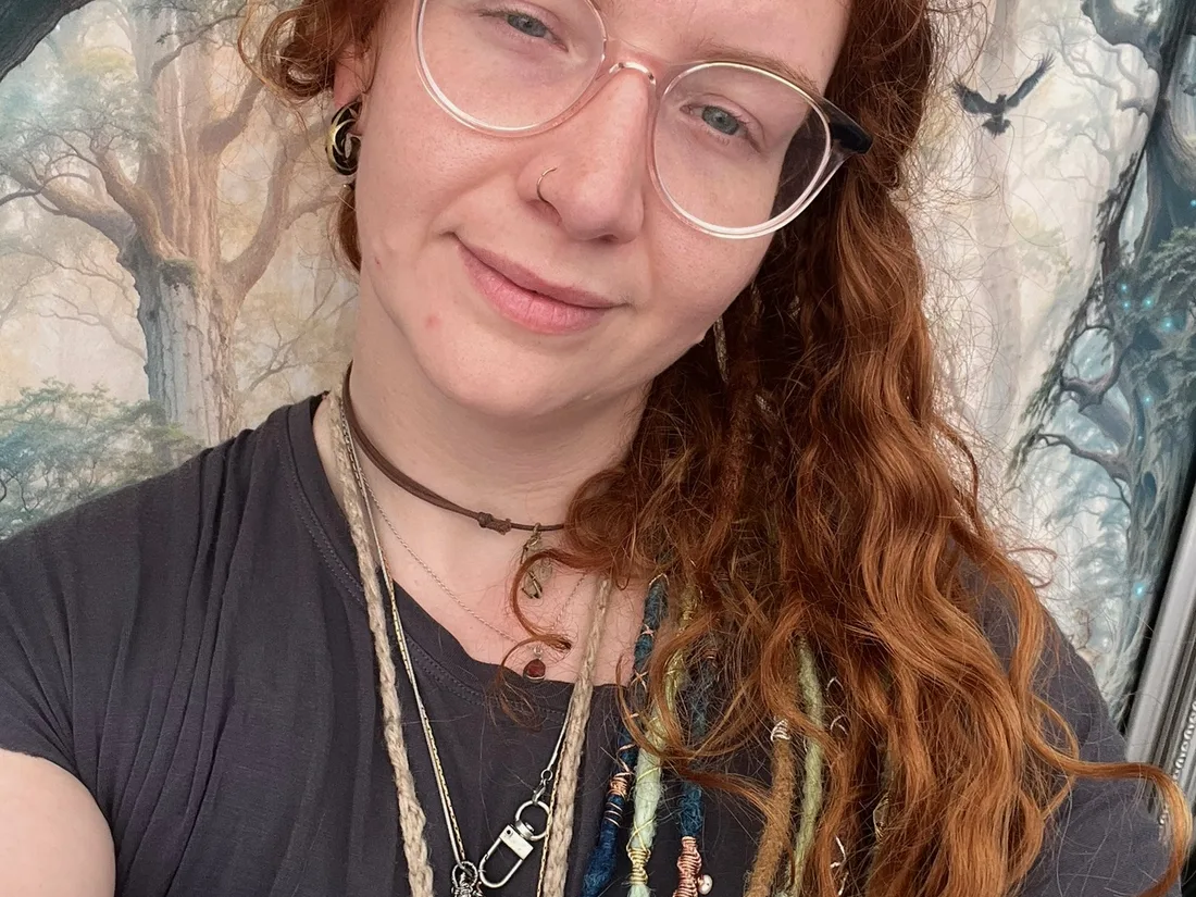 Charlie wearing jewellery in front of a colourful tapestry background.