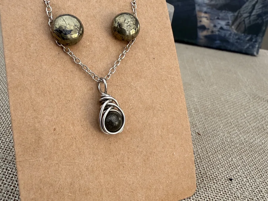 Wire-wrapped jewellery pieces displayed on a brown board.